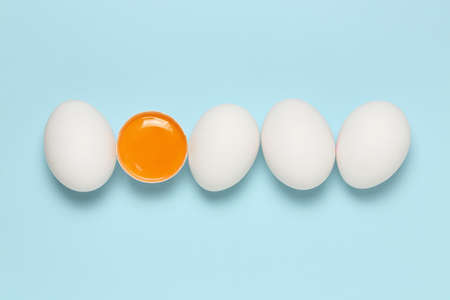 whole eggs and egg yolk on blue, top viewの写真素材