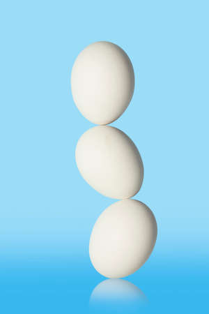 three eggs in balance isolated on blue backgroundの写真素材
