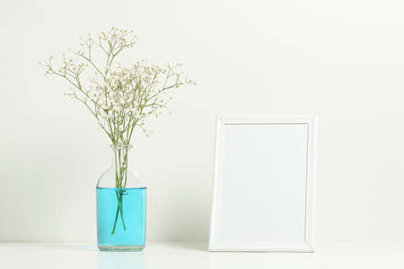 empty picture frame and gypsum flower in vase on book shelf の写真素材