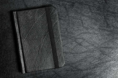 black leather agenda book on black surface, top viewの写真素材