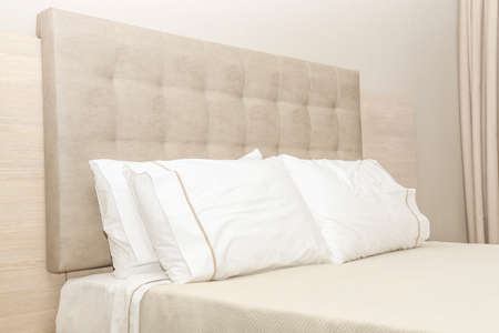 Hotel bedroom, clean pillows and leather headboard, modern colors