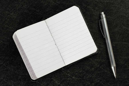 open and blank agenda book with pen on black surfaceの写真素材