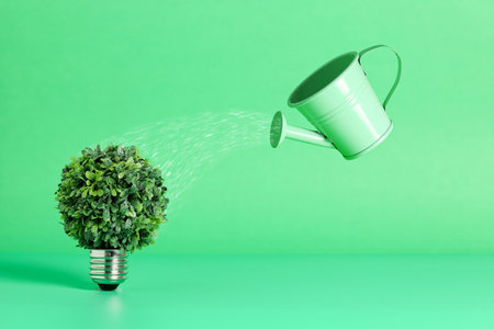 light bulb with tree and watering can on green, growth concept