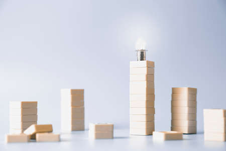 lit light bulb on the tallest stack of blocks, standing out from the crowd conceptの写真素材