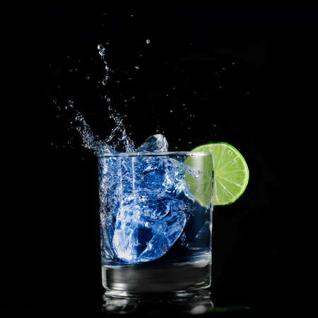 blue drink with lime slice and ice on blackの写真素材