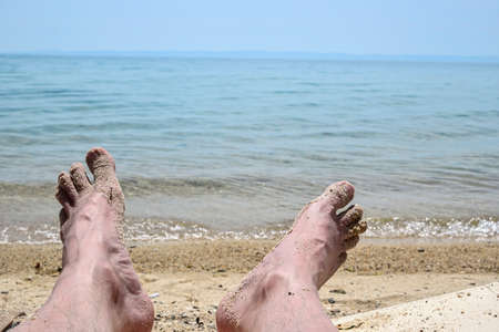 closeup of man's feet relaxing by the sea