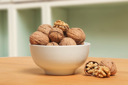 white bbowl of walnuts on wooden surface