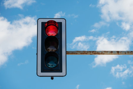 closeup of traffic light with red light on, blue sky