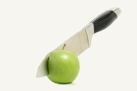 knife cutting green apple in half isolatedの写真素材
