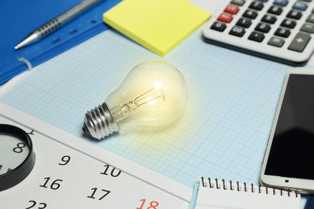 lit light bulb on desk, business conceptの写真素材