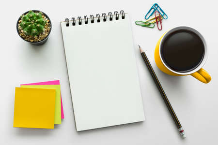 Notebook on office table with a cup of coffee, plant, stationery and office supplies. Blank notepad...