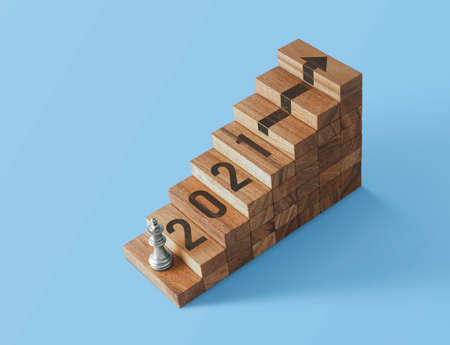 A king chess is on the first step of wooden stacked staircase with the word 2021.の写真素材