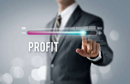 Profit growth, increase profit, raise profit or business growth concept. Businessman is pulling up progress bar with the word PROFIT on bright tone background.の写真素材
