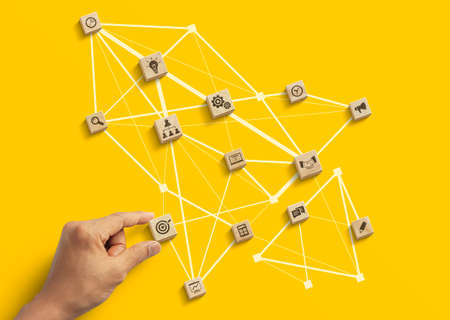 Business strategy to success, business management or start up business concept. Hand is arranging wooden blocks with business icon in low polygon rocket shape network on yellow background.の写真素材