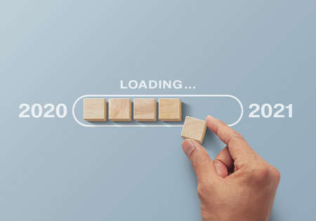 2021 uploading, reboot, refresh or mindset concept. Hand putting wooden blocks in progress bar on gray background with the word 2021 uploading.の写真素材
