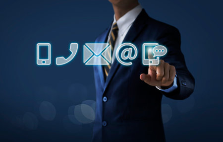 Customer service, call center service or contact us concept Businessman touching communication icons (mobile phone, telephone, mail, email address, social media) on dark tone background.の写真素材