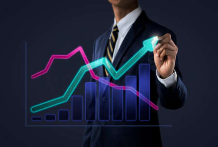 Business growth, progress or success concept. Businessman is drawing a growing 3d virtual hologram graph on dark tone background.の写真素材