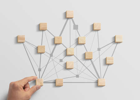 Human resources management, teamwork management or business strategy to success concept. Hand is arranging wooden blocks in low polygon crown shape network on white background.の写真素材