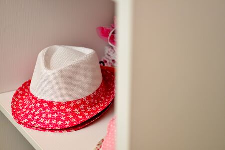 White and floral red hat on shelfの写真素材