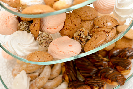 Cookies, marshmallows, eclair, chocolate balls with nuts placed on glass support