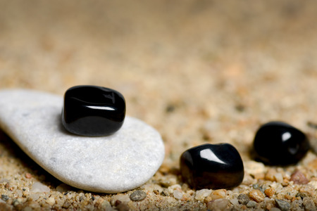 Gray and black stones in sand backgroundの写真素材