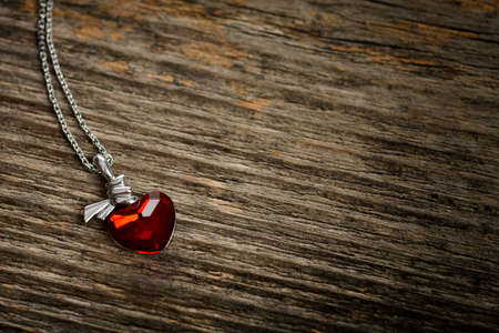 Red heart-shaped pendant on wood textureの写真素材