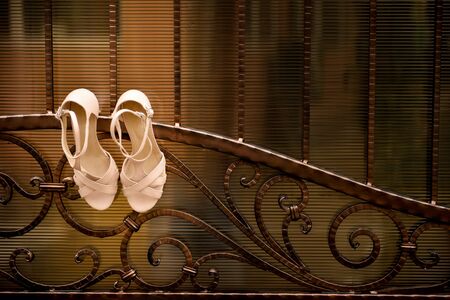 White wedding shoes hang a wrought iron fenceの写真素材