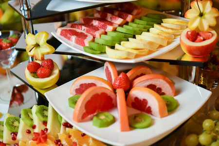 Plates with different type of fruits: strawberry, pineapple, orange, kiwiの写真素材
