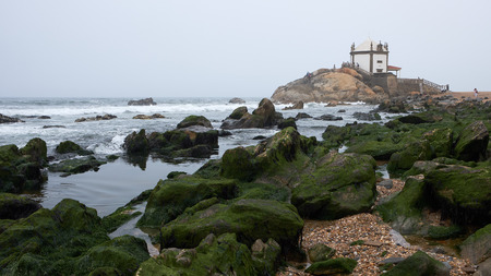 Vila Nova de Gaia, Portugal - September 30, 2018 : Empty tide reveals the mossy rocks near the chapel, Porto district, Portugalのeditorial素材