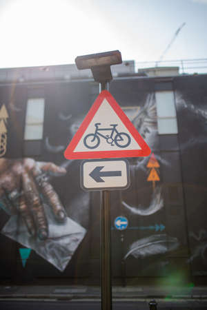 A Triangular Bicycle Sign with a Colorful Mural in the Background