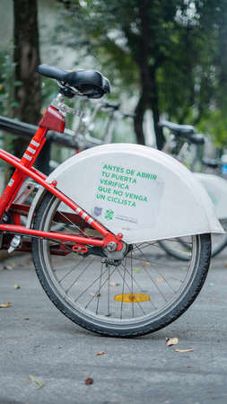 Warning Sign on the Back Wheel of a Public Bicycle Parked on the Street