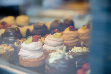 Chocolate and Cream Muffins and Cupcakes Through the Window of a Bakeryの写真素材