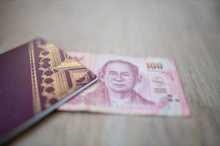 One Hundred Thai Baht Bill Partially Inside a Sweden Passportの写真素材