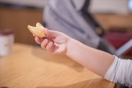 The Hand of a Little Girl Holding a Furtune Cookie with a Blurry Backgroundの写真素材