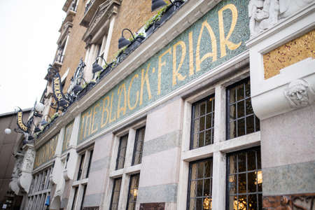 British pub with its green and golden signboard on a wall over some windows