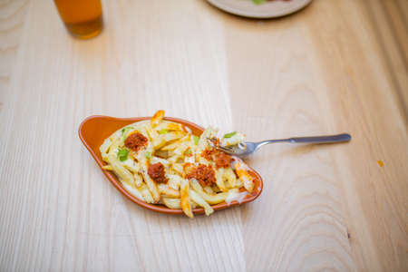 Fork on an air fried fries and sundried tomatoes dish on a wooden table