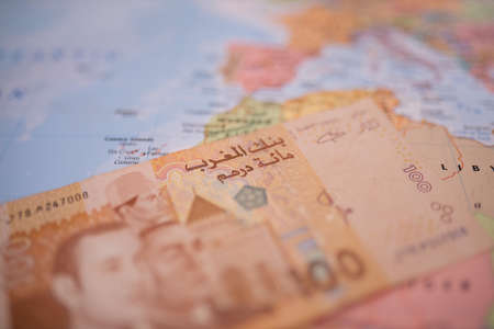 One hundred Moroccan dirham bill below Morocco on a colorful and blurry map
