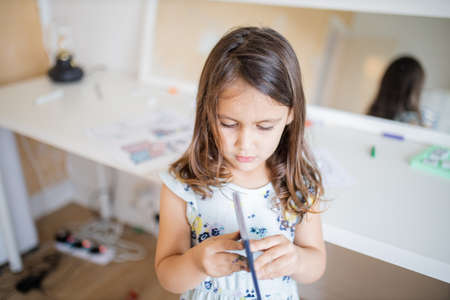 Little girl looking at an American passport with a desk and a mirror behind her