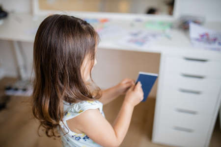 Little girl looking at an American passport in front of a desk and a mirror