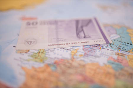 Fifty Danish kroner bill above Denmark on a colorful and blurry map of Europeの写真素材