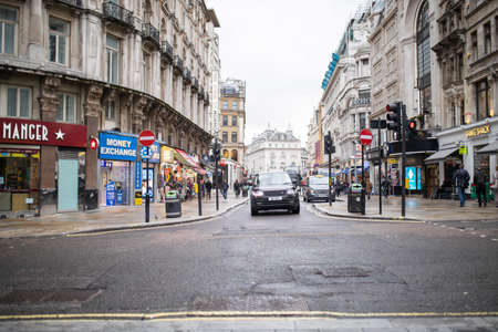 Black car driving in a narrow one-way street between two classic buildingsの写真素材