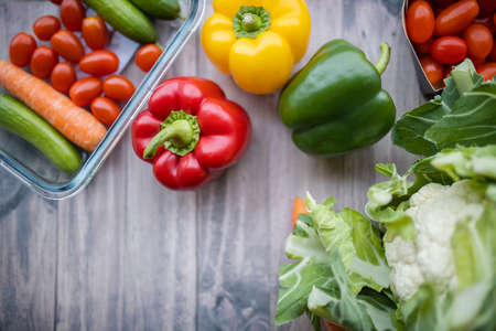 Fresh and colorful bell peppers and other vegetables on wooden tableの写真素材