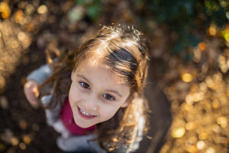 Happy little girl looking up and smiling from aboveの写真素材