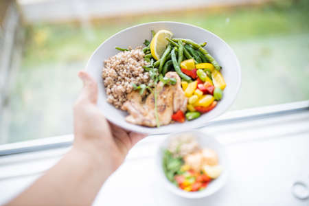 Hand holding a chicken and buckwheat dish with green beans