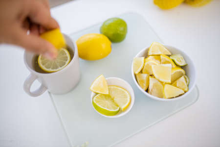 Female hand squeezing lemon into a cup of lemon teaの写真素材
