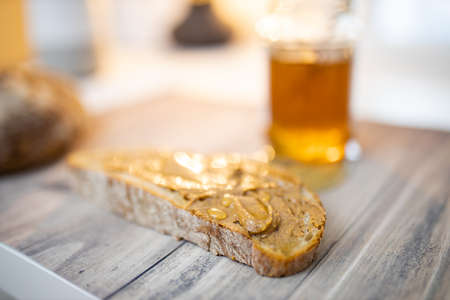 Slice of bread with peanut butter and a honey jar on wooden table