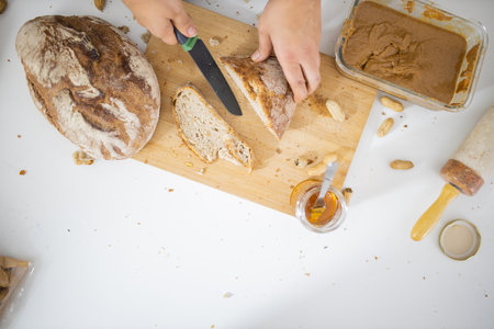 Female hands slicing bread on a cutting boardの写真素材