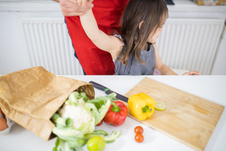 Father and daughter at a table getting ready to cut vegetablesの写真素材