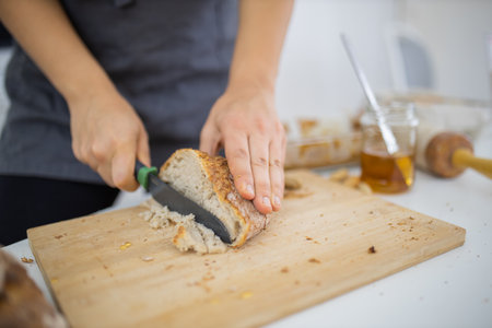 Female hands slicing bread on a cutting board