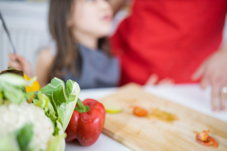 Little girl and her father slicing vegetables on a cutting boardの写真素材